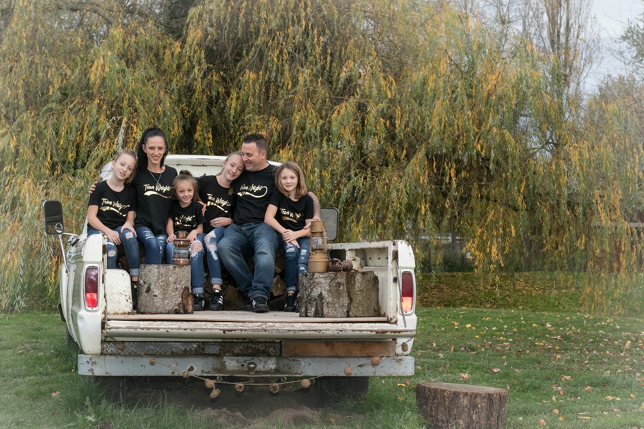 A family sits on a rustic truck bed, surrounded by a natural setting